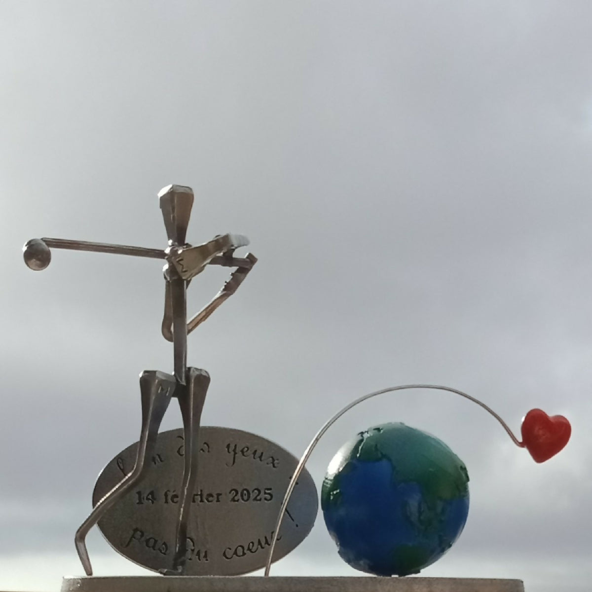 Statuette de golfeur métal doré avec globe bleu-vert et petit cœur rouge en tige