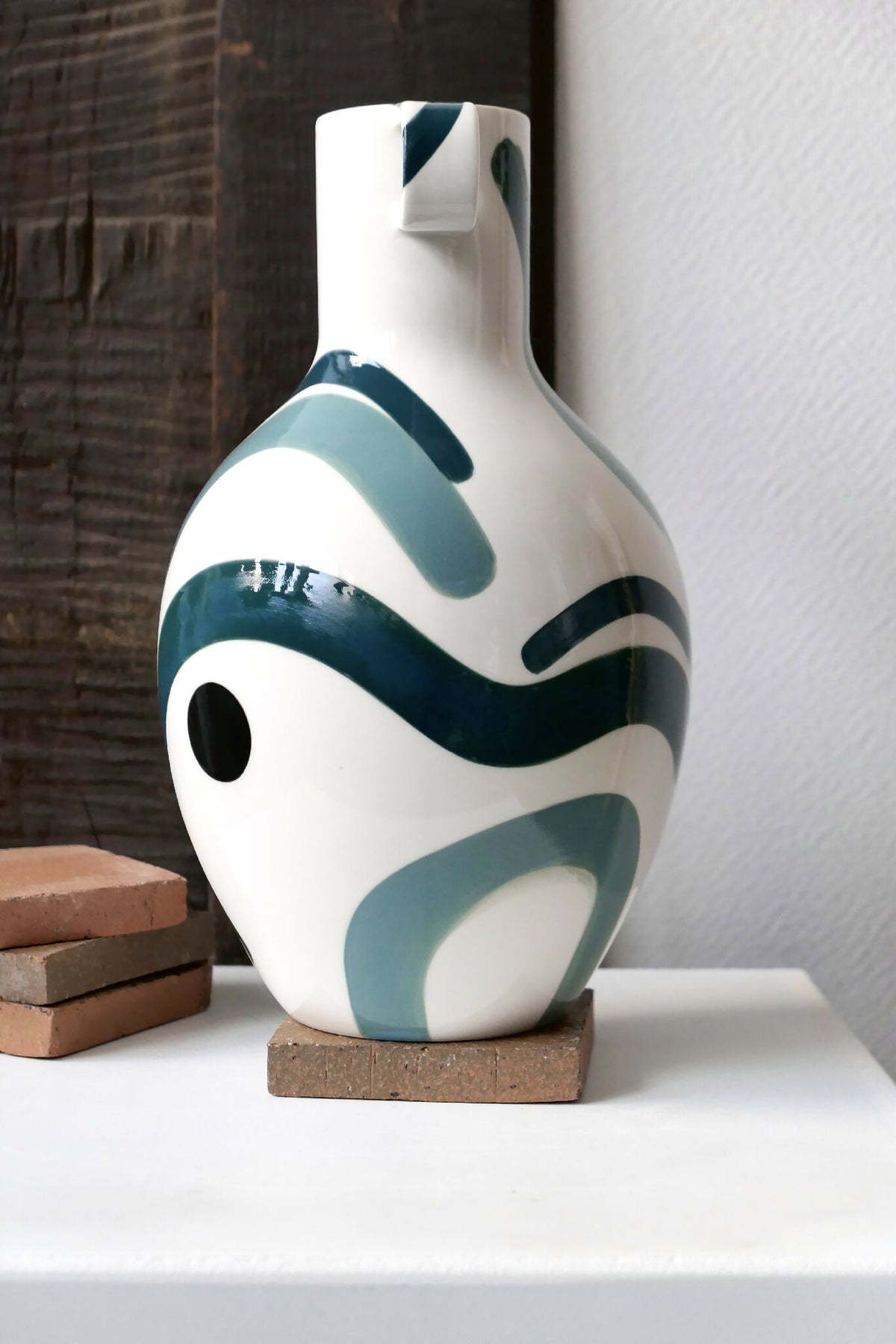 Vase buste en céramique blanche, anses, décor vert/turquoise et formes sombres.