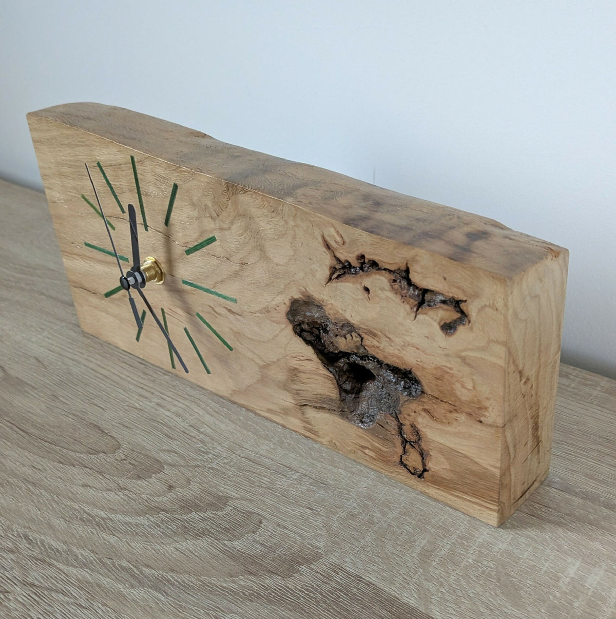 Horloge de bureau en bois clair, aiguilles noires et repères verts sur face inclinée.