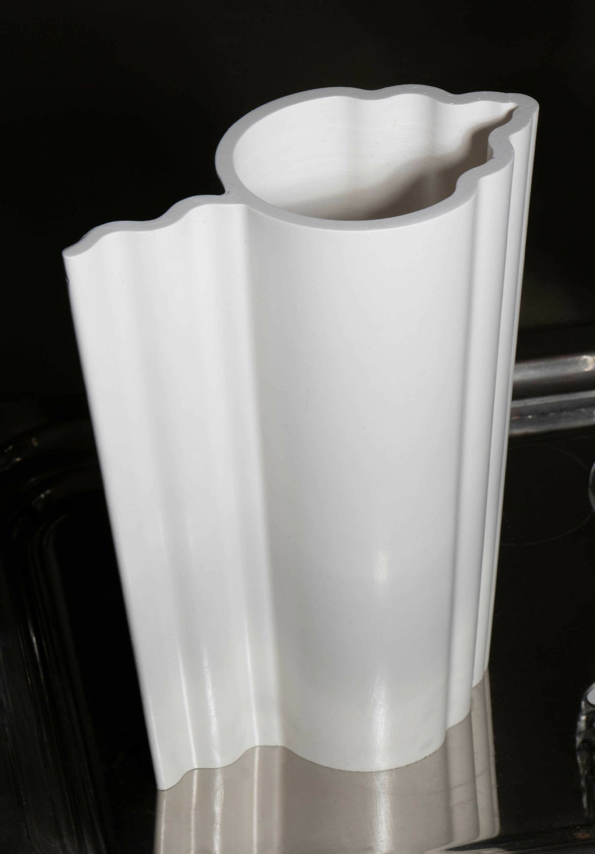 Vase blanc à profil nervuré avec bord supérieur évasé et ondulé, vue rapprochée.