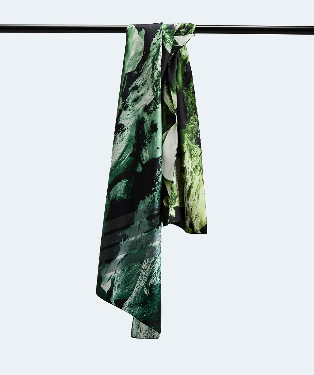 Écharpe en tissu fluide à motif vert et noir, drapée sur une barre