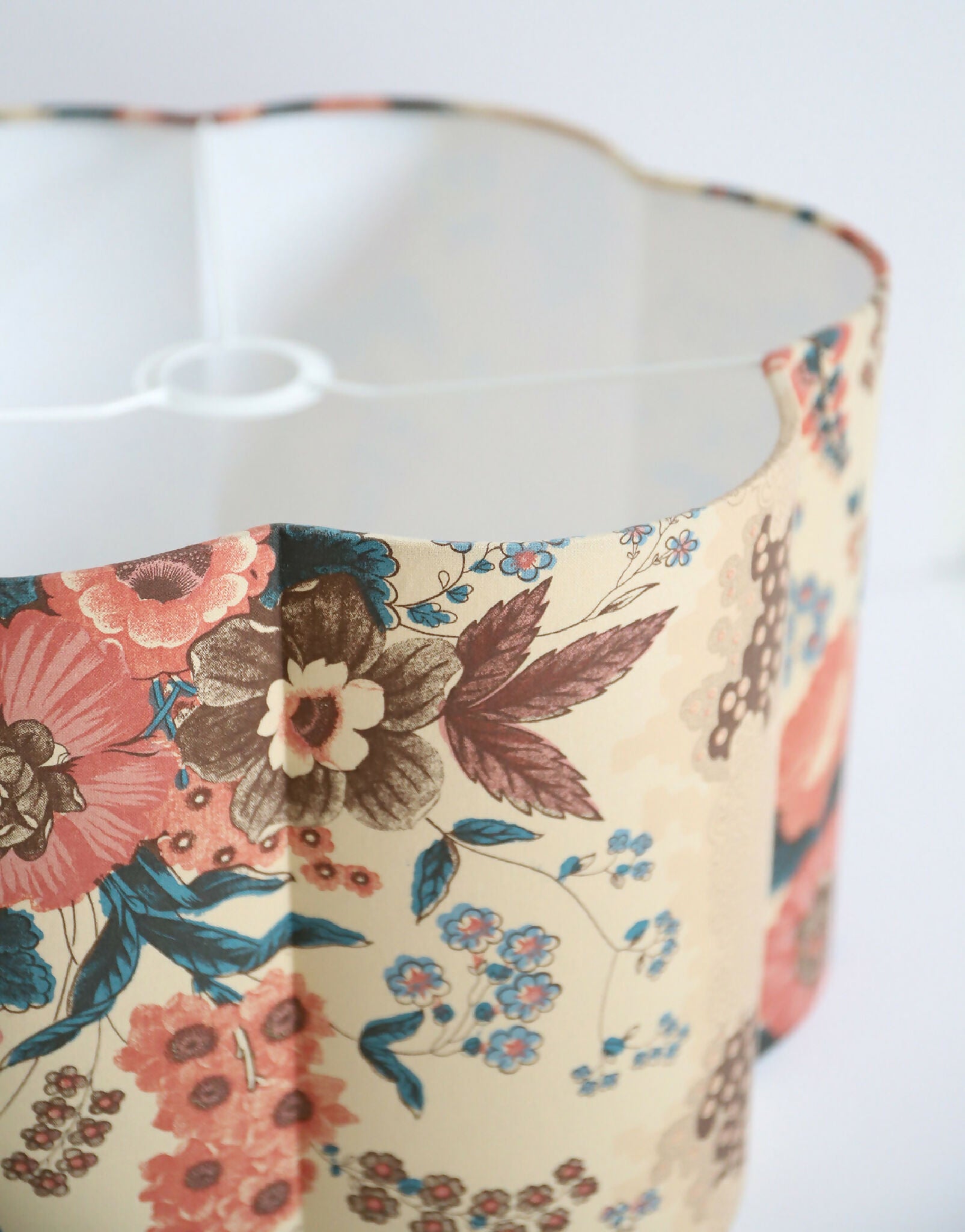 Abat-jour forme fleur : motif floral rouge, bleu et brun sur fond crème, vue latérale.