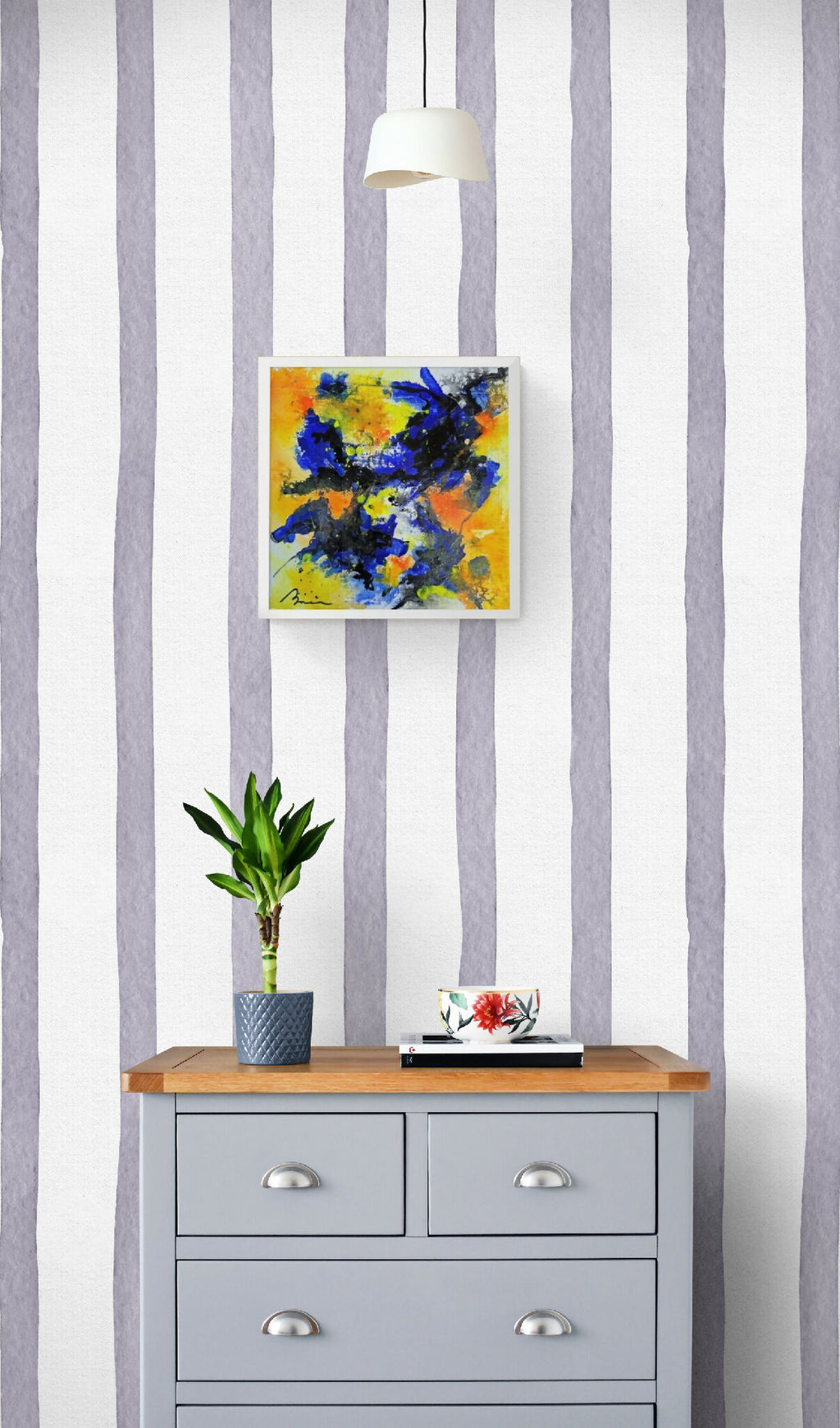 Peinture encadrée Interstellaire sur mur à rayures, au-dessus d’une commode