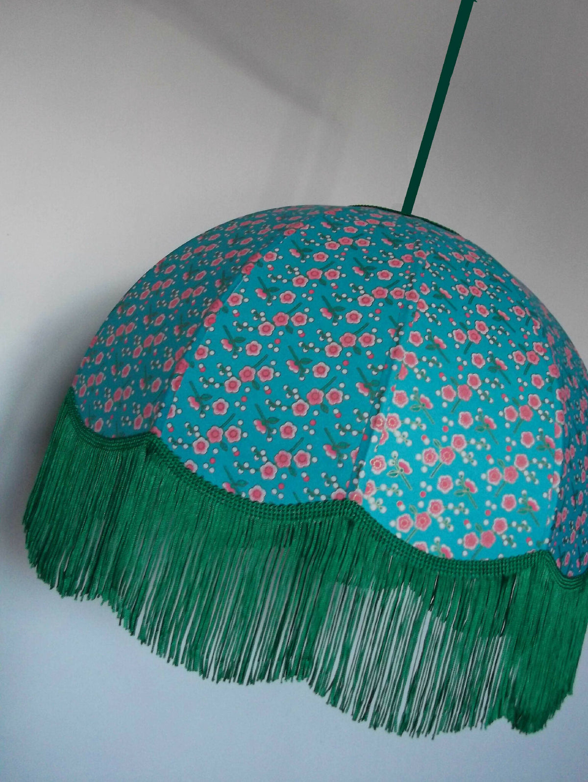 Suspension ronde en papier bleu turquoise à fleurs, franges vertes et cordon vert.