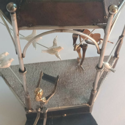 Intérieur de manège décoratif : figurines, arche métallique et surface tissée grise.