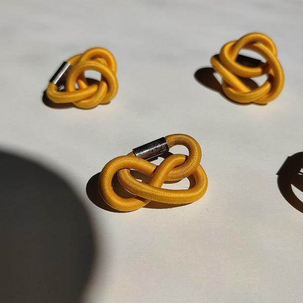 Broche en cordon tressé jaune, motif entrelacé et attache métallique visible
