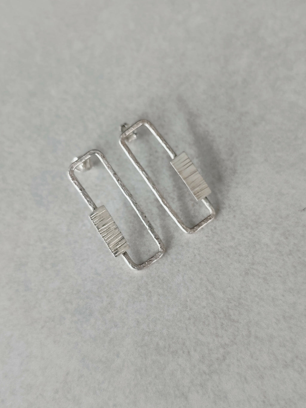 Boucles d’oreilles rectangulaires argentées, vue de face des deux pièces.
