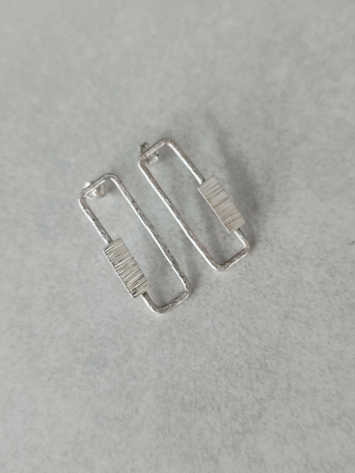 Boucles d’oreilles rectangulaires argentées, vue de face des deux pièces.