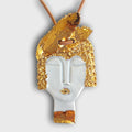 Pendentif visage féminin doré et blanc, détail yeux et bouche, attache pour cordon