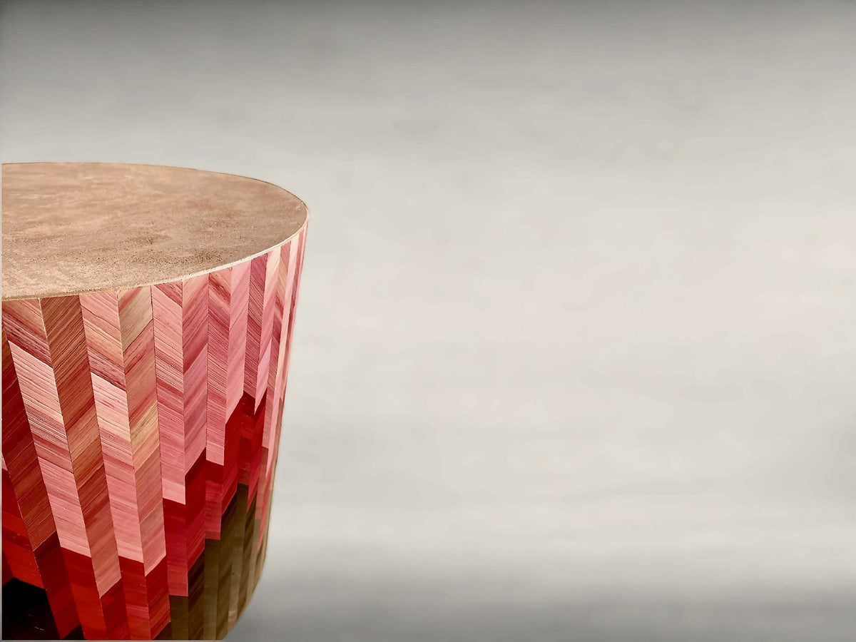 Bout de canapé rond, vue de côté : motif chevrons rouge sur base sombre.