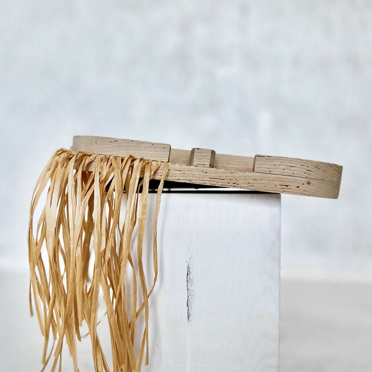 Masque décoratif en fibres de paille tressées avec attache suspendue et relief sculpté.