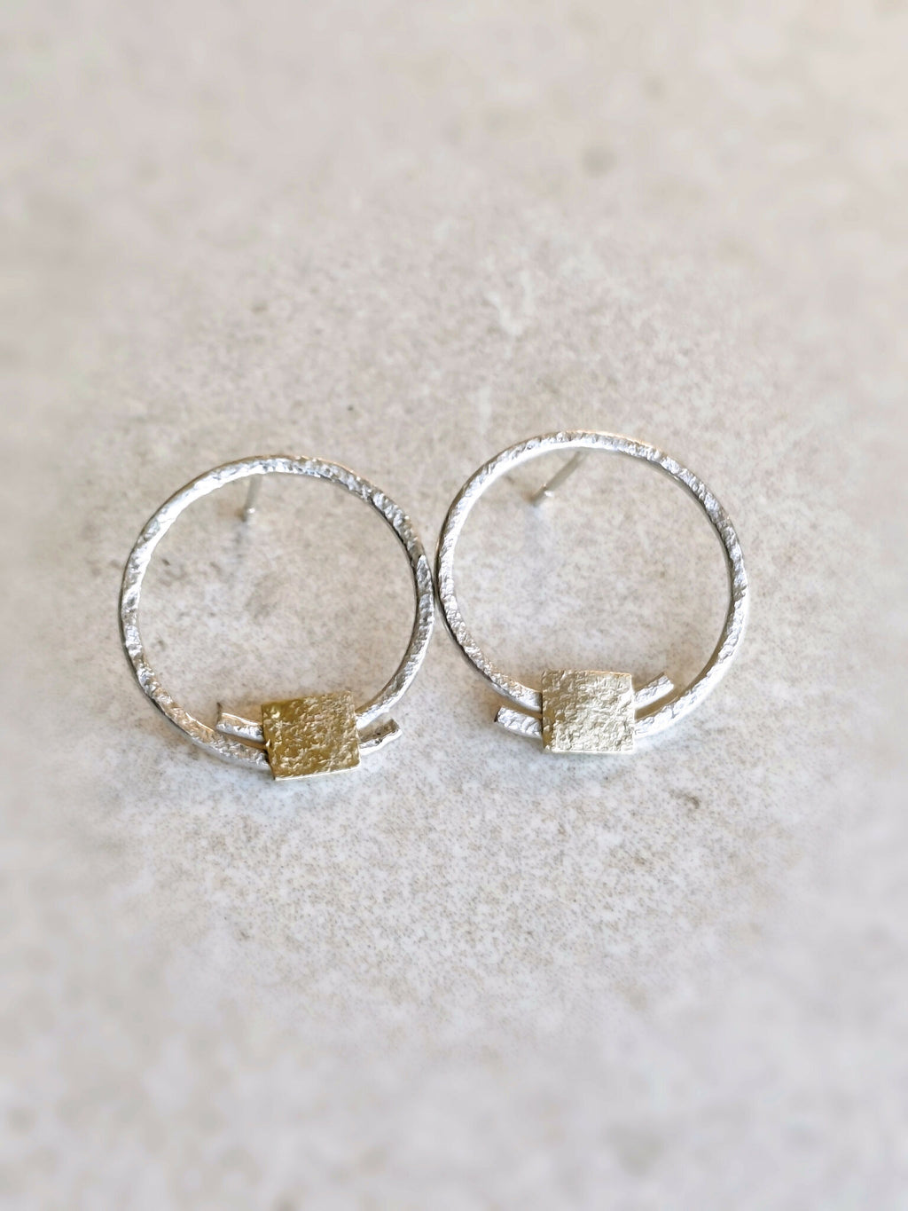 Boucles d’oreilles créoles argentées avec pastilles carrées dorées, vue de face