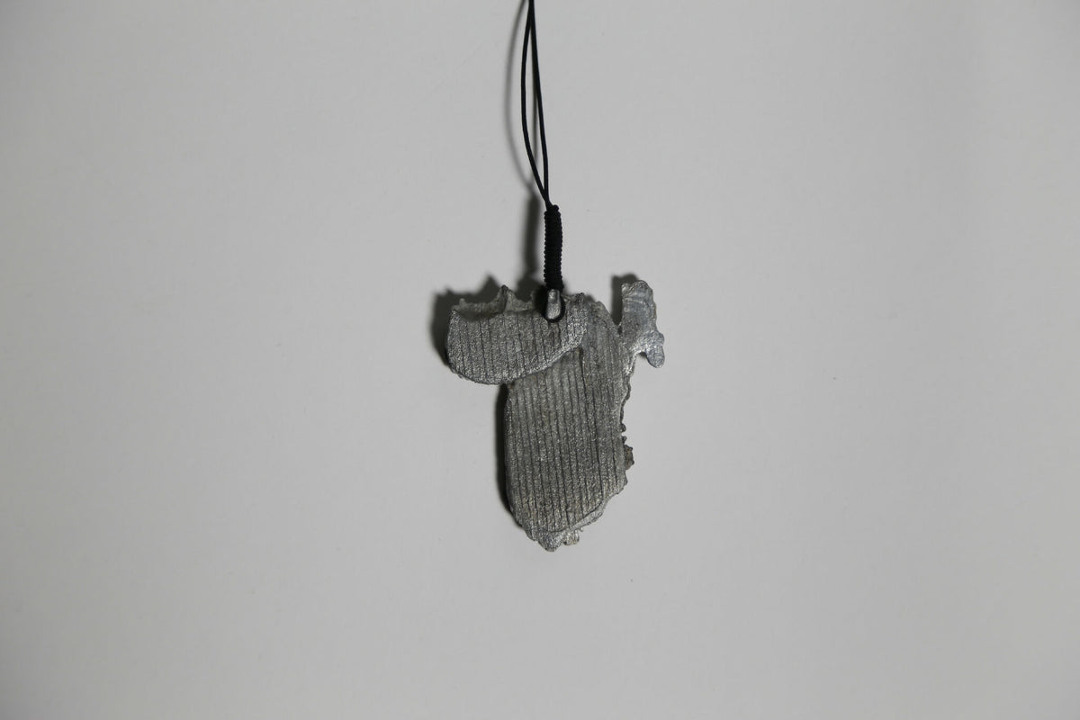 Pendentif gris en forme de feuille, vue de face, texture striée, sur cordon.