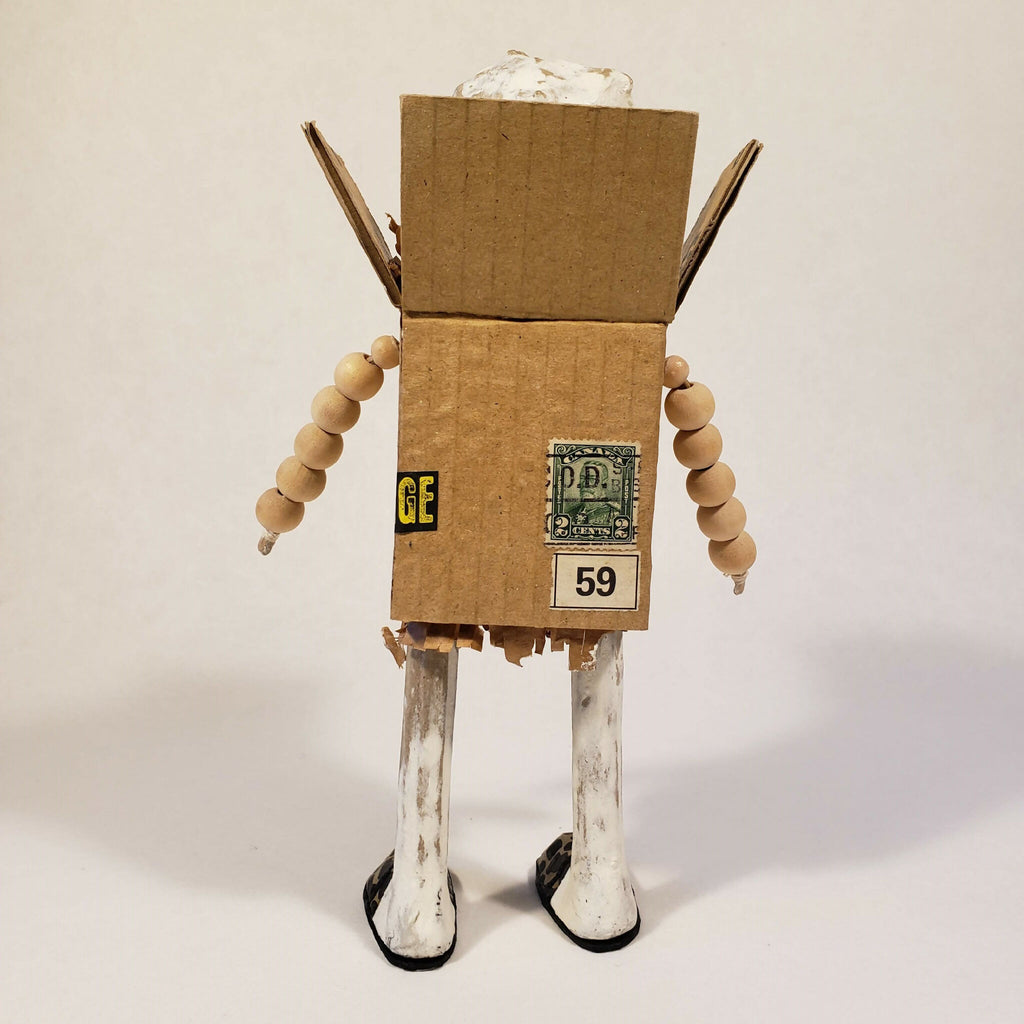 Sculpture bonhomme en carton, jambes blanches et marquage 59 sur la boîte