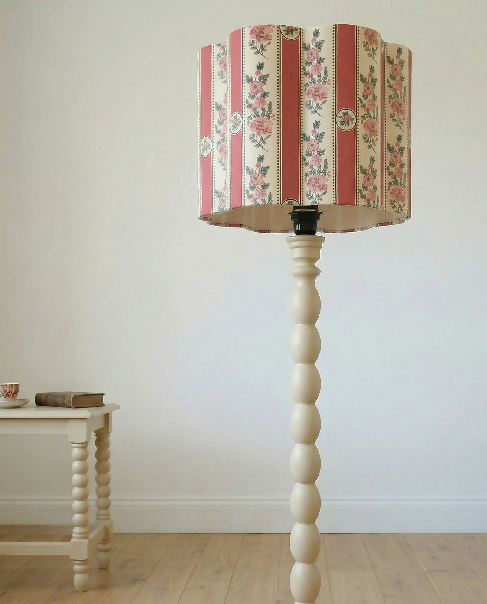 Abat-jour forme fleur rayé rose fleuri, sur lampe avec base bois claire.