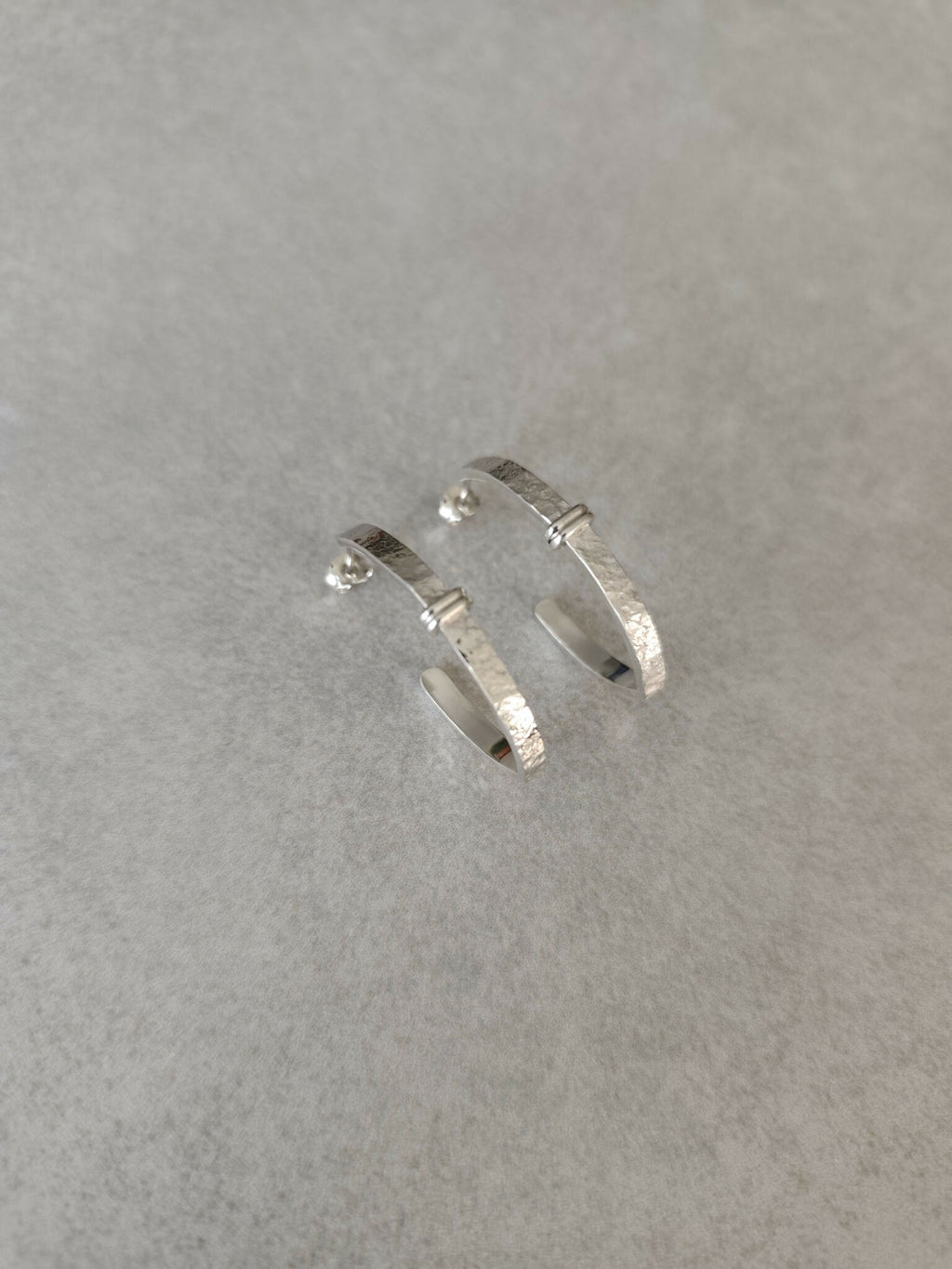 Boucles d’oreilles courbes argentées, surface martelée et charnière entre deux parties