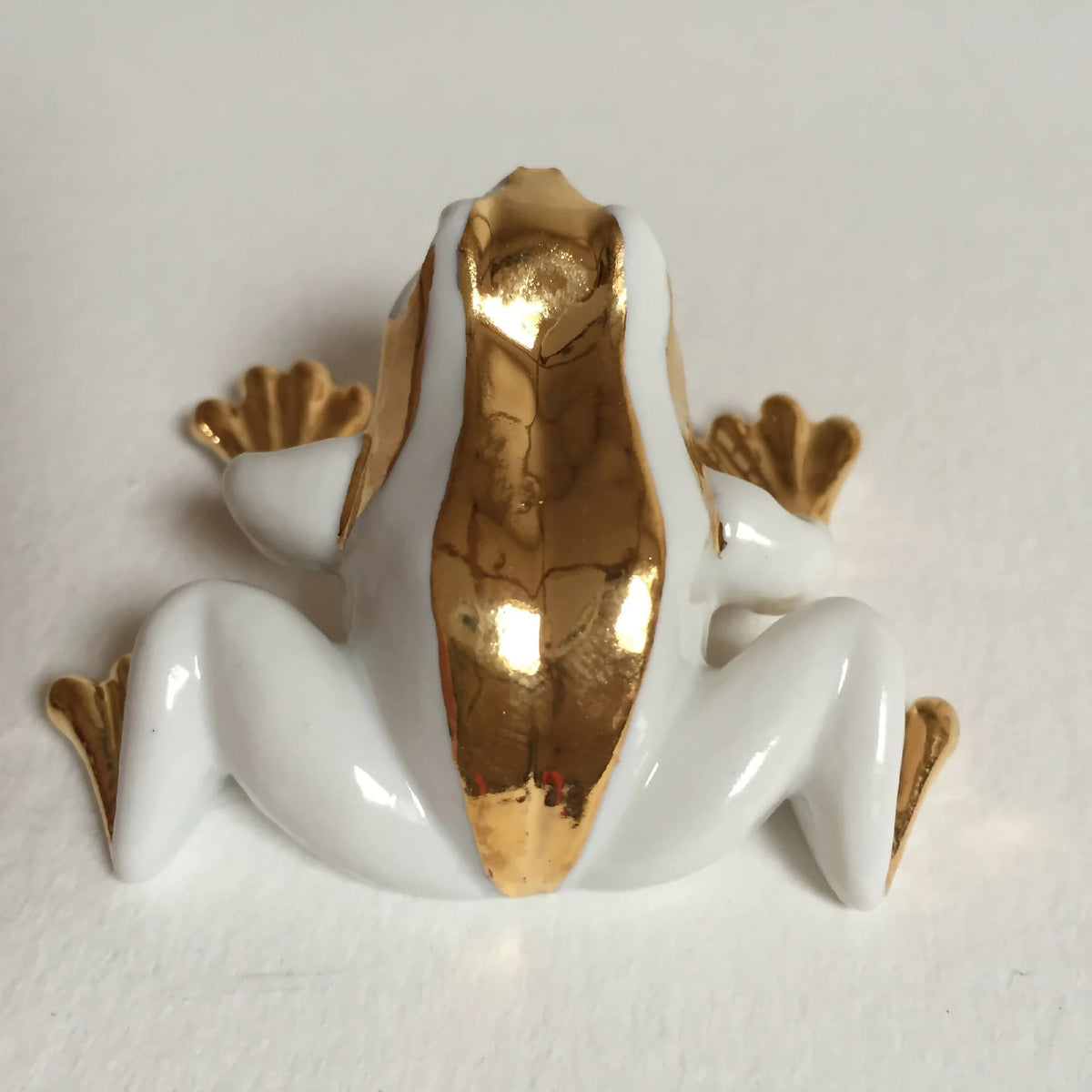 Figurine de grenouille couchée en porcelaine blanche, éclats d’or sur le buste