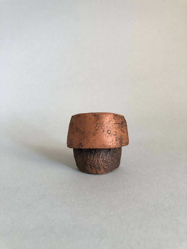 Petite pièce en cuivre rouillé ajourée, forme concave, vue de face.