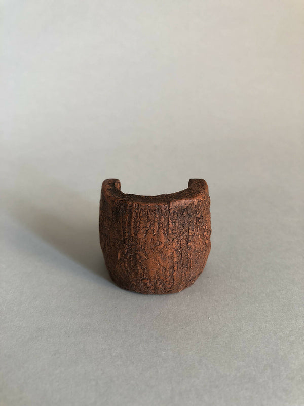 Petit objet concave en matière brune texturée, ouverture en haut