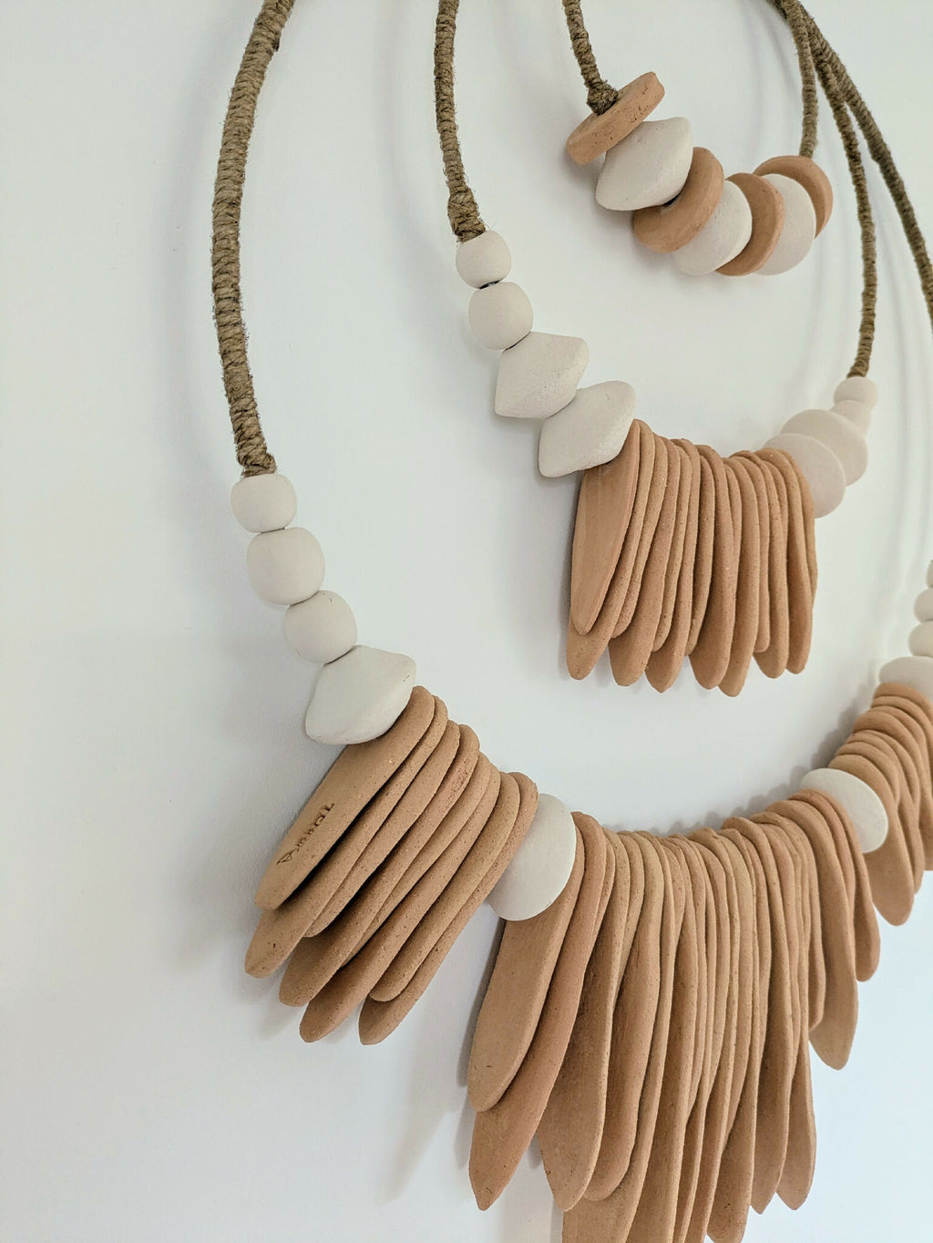 Décoration murale XXL en cordons avec perles, tons terracotta et blanc, détail de motif