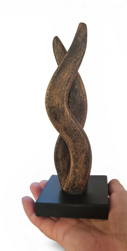 Sculpture bronze en forme de flamme, tenue par une main, sur socle noir