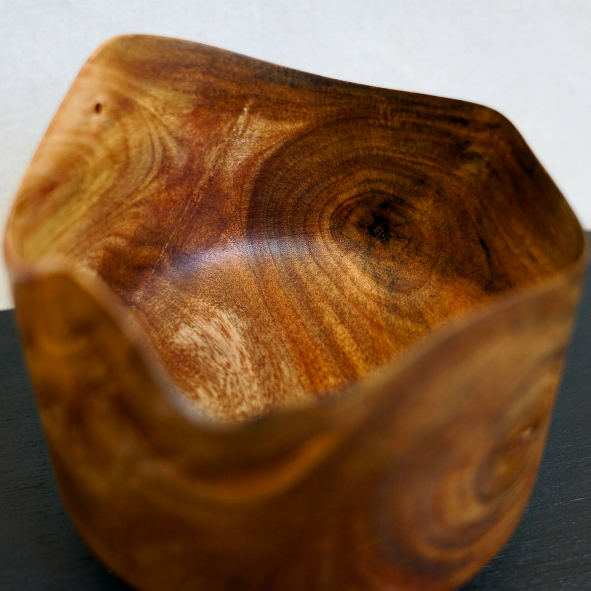 Bol en bois naturel, finition lisse, forme courbée et grain visible