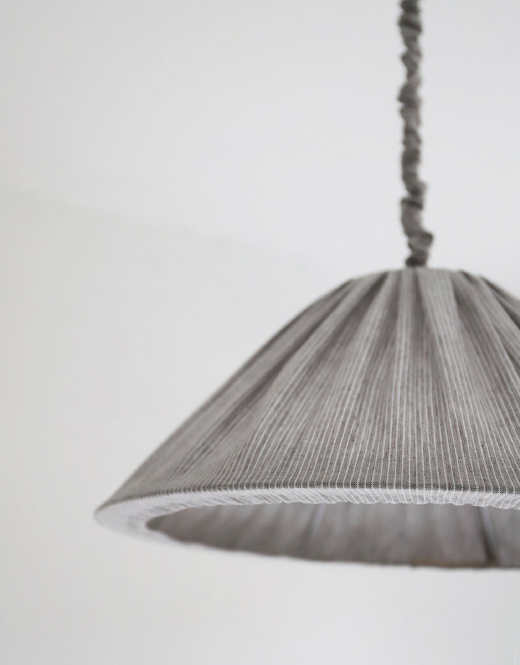 Abat-jour plissé gris à fines rayures, détail du bord et de la couture