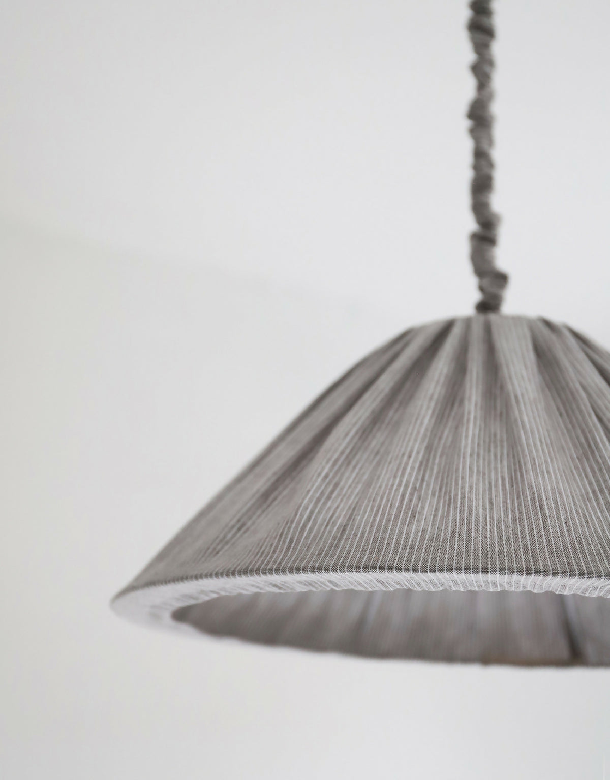 Abat-jour plissé gris à fines rayures, détail du bord et de la couture