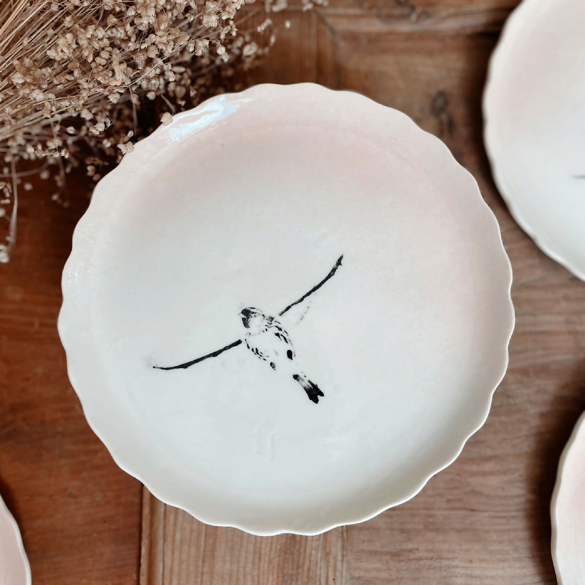 Assiette à dessert en porcelaine blanche, bord festonné, oiseau noir au trait central