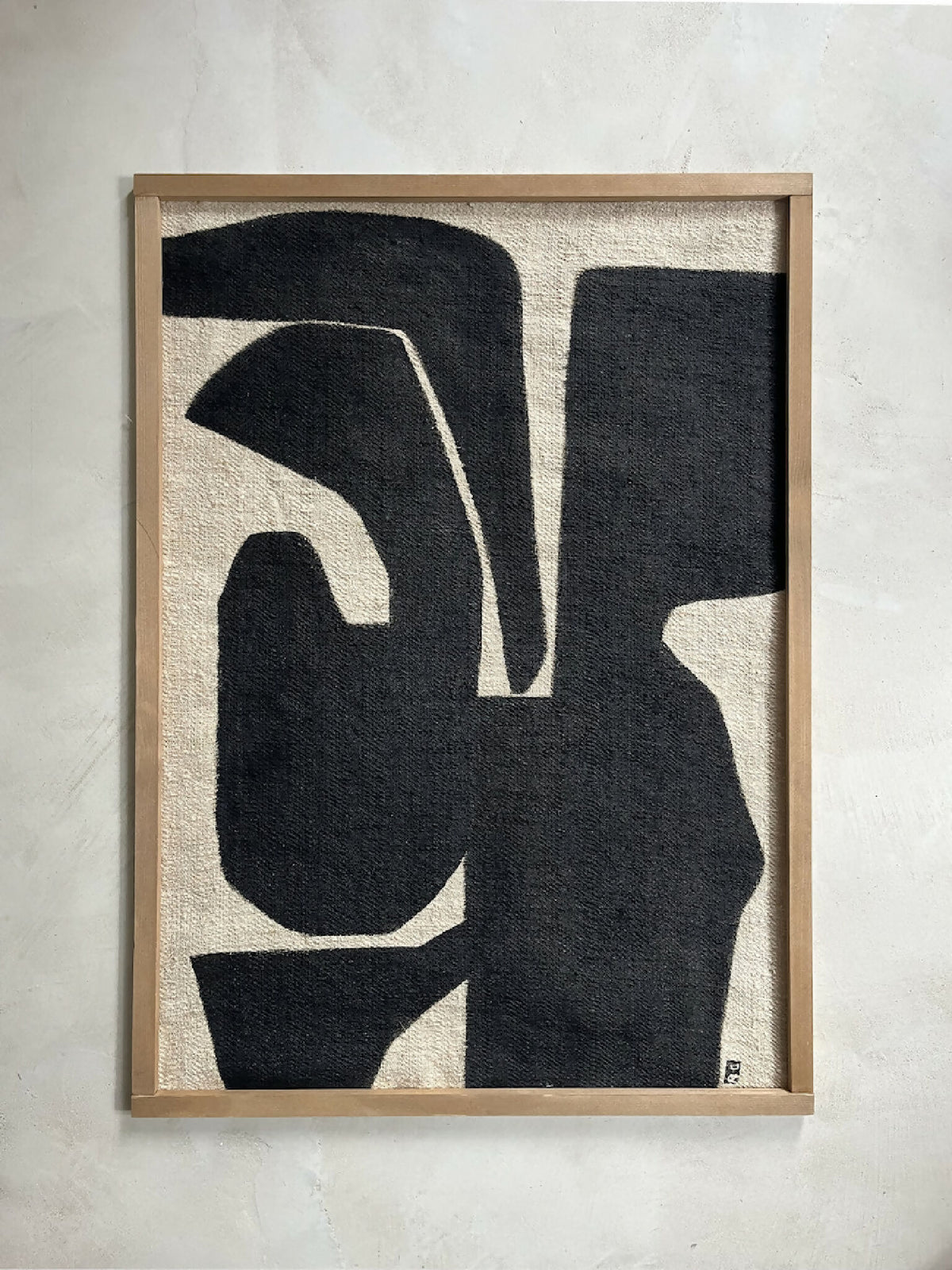 Tableau abstrait Kawi : formes noires sur fond clair, cadre en bois clair.