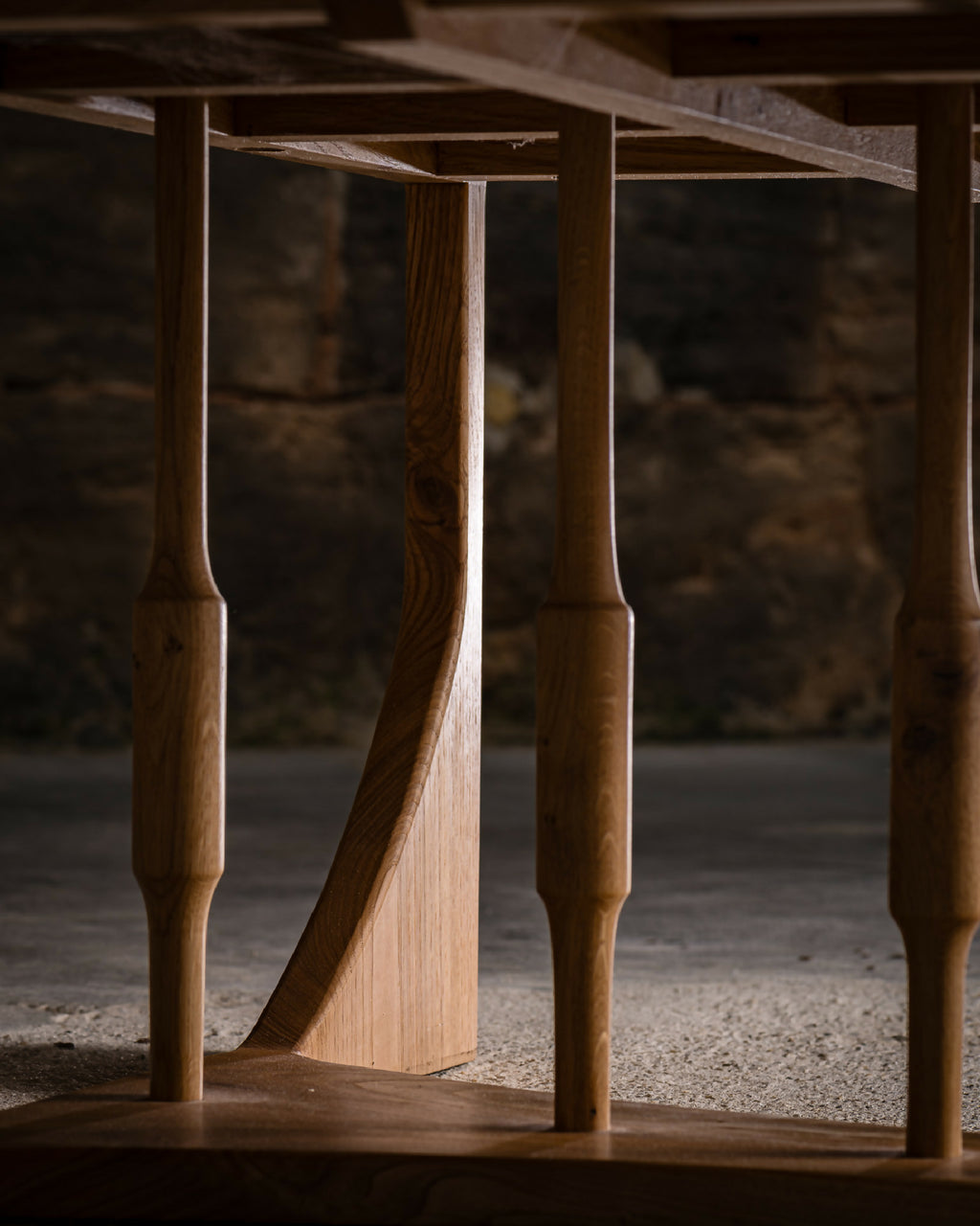 Table basse en bois clair : détail du piétement tourné et de la base sous le plateau