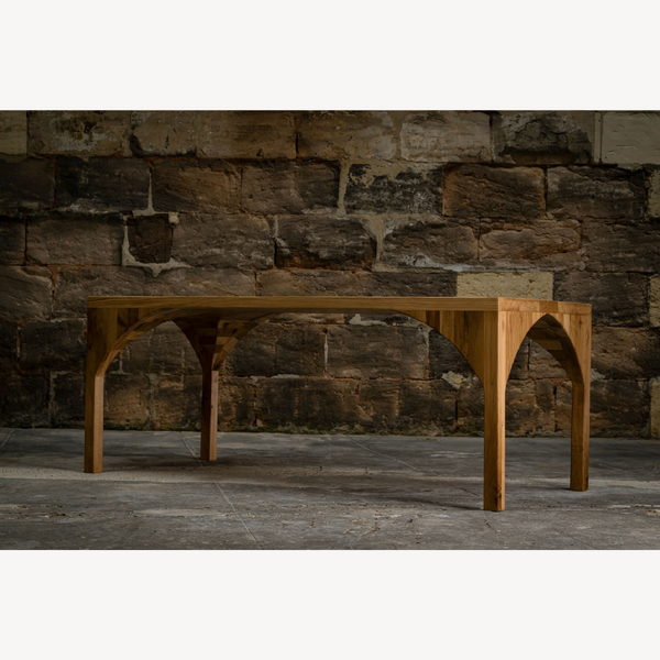 Table en bois massif avec structure en arc, vue en perspective.
