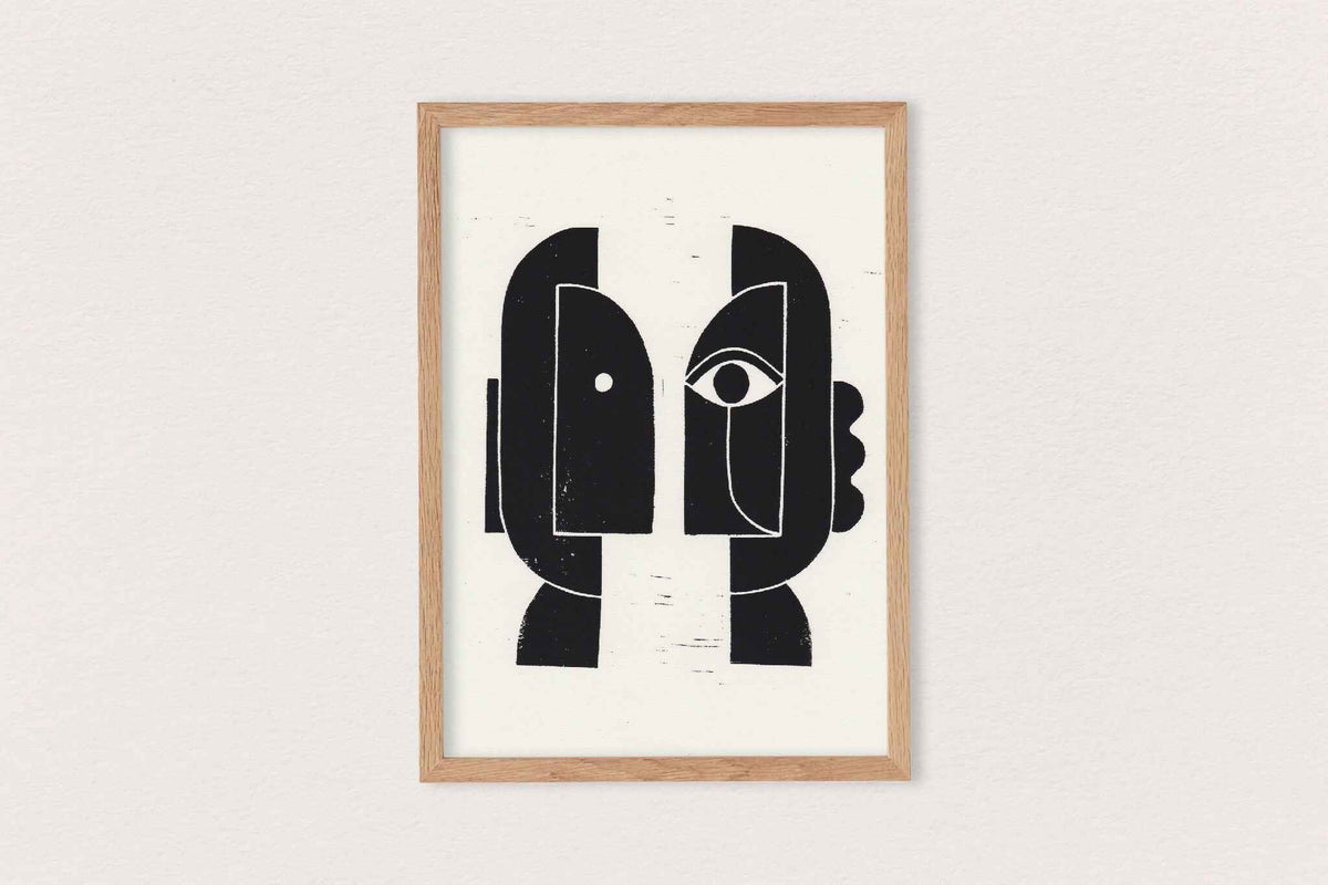 Linogravure encadrée, composition noire de visages stylisés sur fond clair