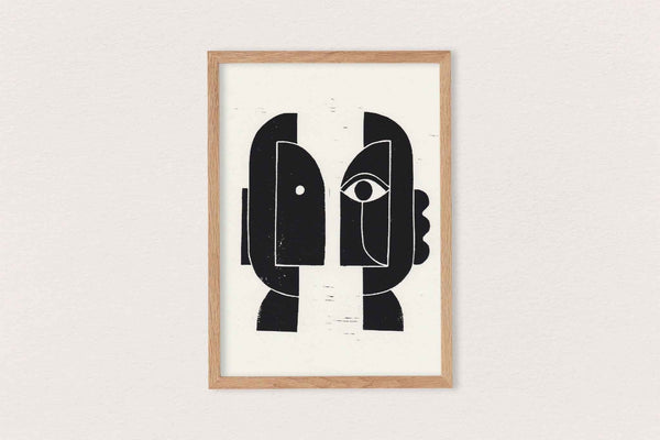 Linogravure encadrée, composition noire de visages stylisés sur fond clair