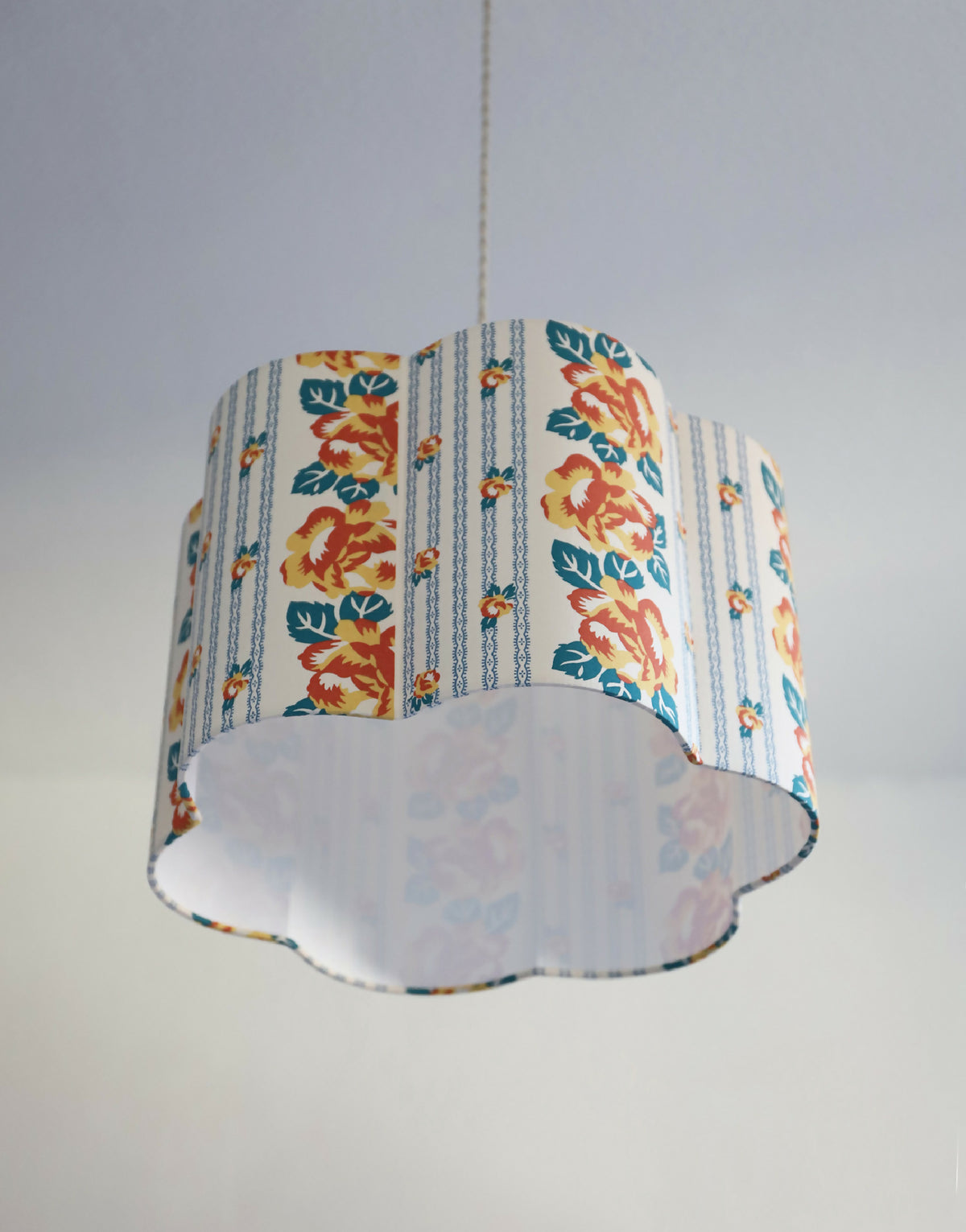 Abat-jour forme fleur en tissu bleu clair, motif floral orange et bases blanches.