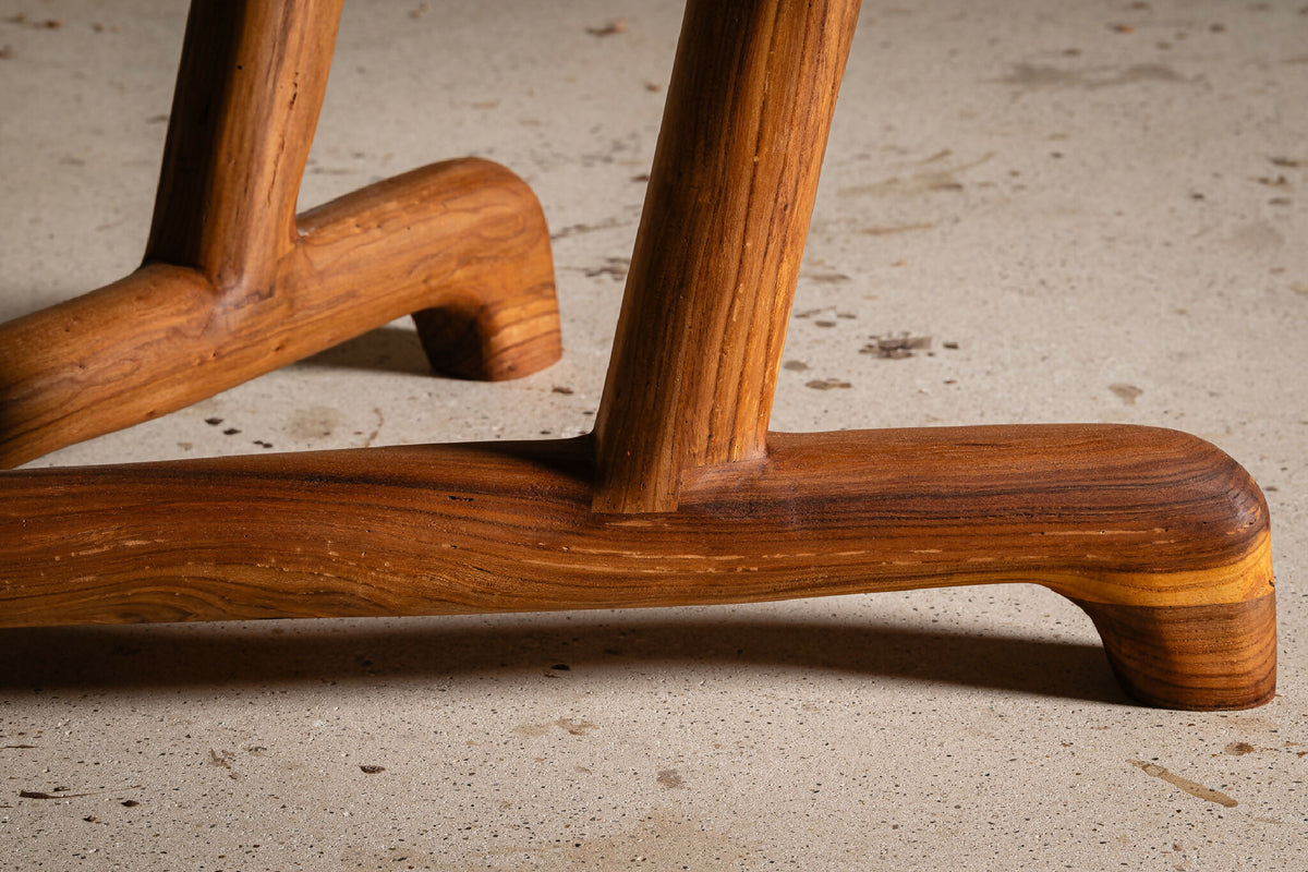 Table en bois massif, gros plan d’un coin avec pied sculpté et base moulurée.