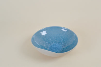 Coupe en céramique blanche à intérieur bleu, vue rapprochée du dessus, bord évasé.