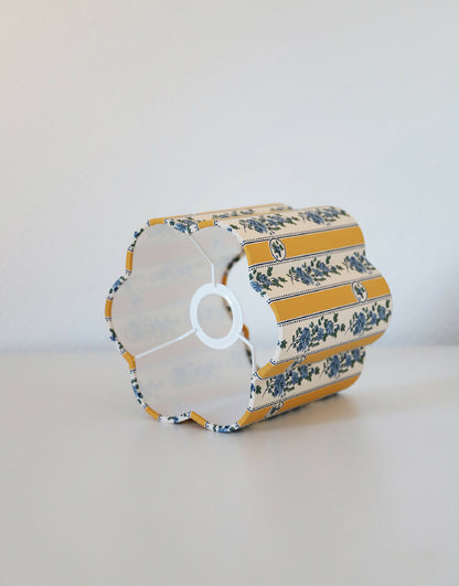 Abat-jour forme fleur en tissu à rayures verticales jaunes et motifs floraux bleus.