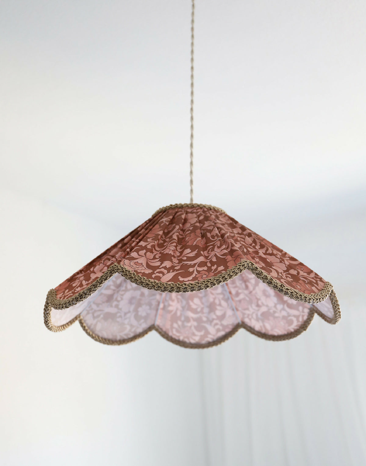 Suspension florale en tissu bordeaux, collerette claire et bordure dentelée.