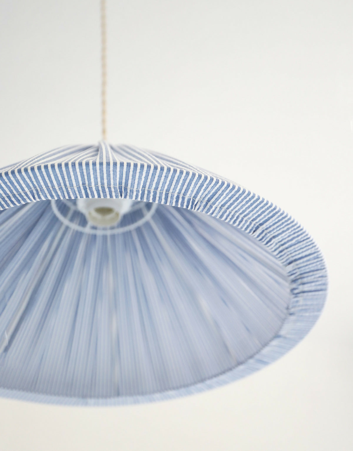 Suspension conique à fines rayures bleues, abat-jour avec base lumineuse.