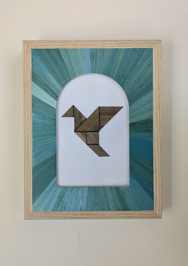 Tableau marqueterie en paille : oiseau géométrique brun et turquoise dans un cadre beige.