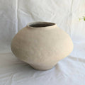 Vase en céramique beige, forme arrondie avec ouverture évasée.