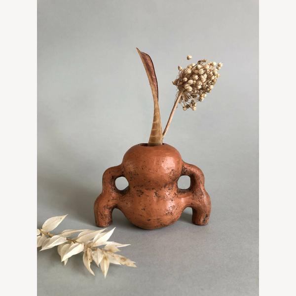 Vase à herbes sèches en terre cuite orange, tige et bouquet sec dans l’ouverture