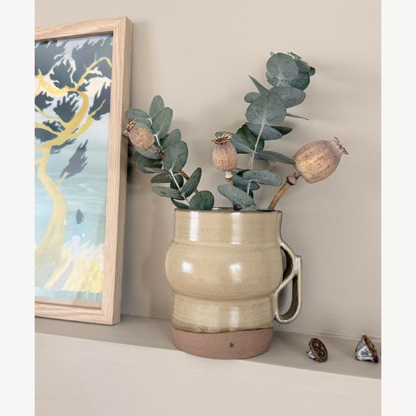 Vase Désert n°3 en céramique beige à anses, avec feuilles vertes séchées.