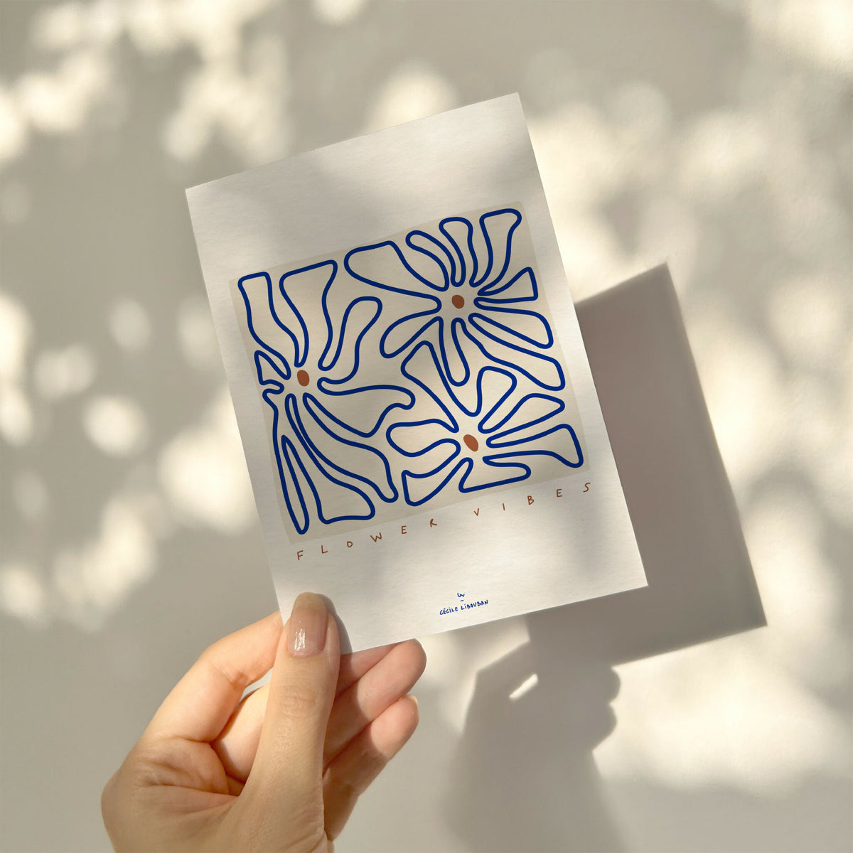 Carte illustrée fleurs abstraites bleues, tenue dans une main.