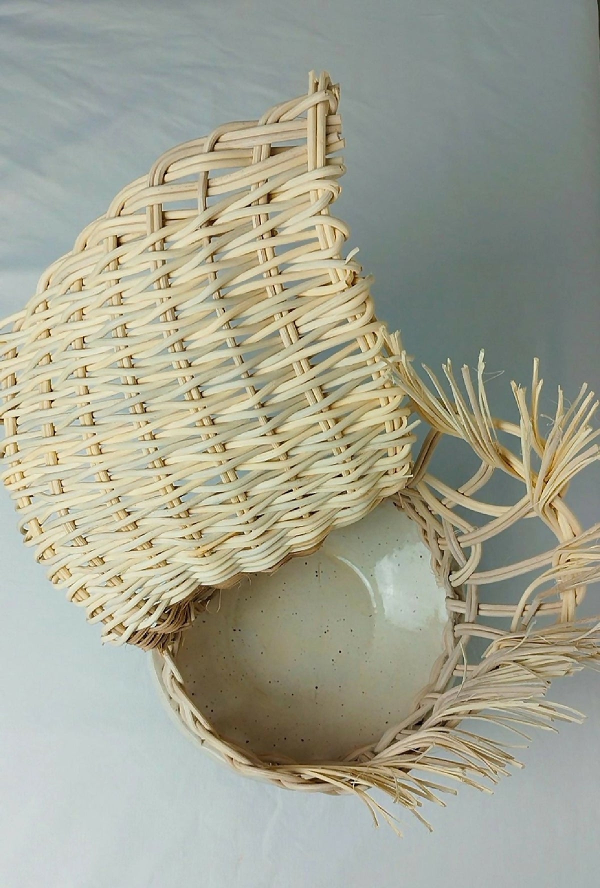 Photophore en osier tressé beige avec ouverture, brins décoratifs et base ronde