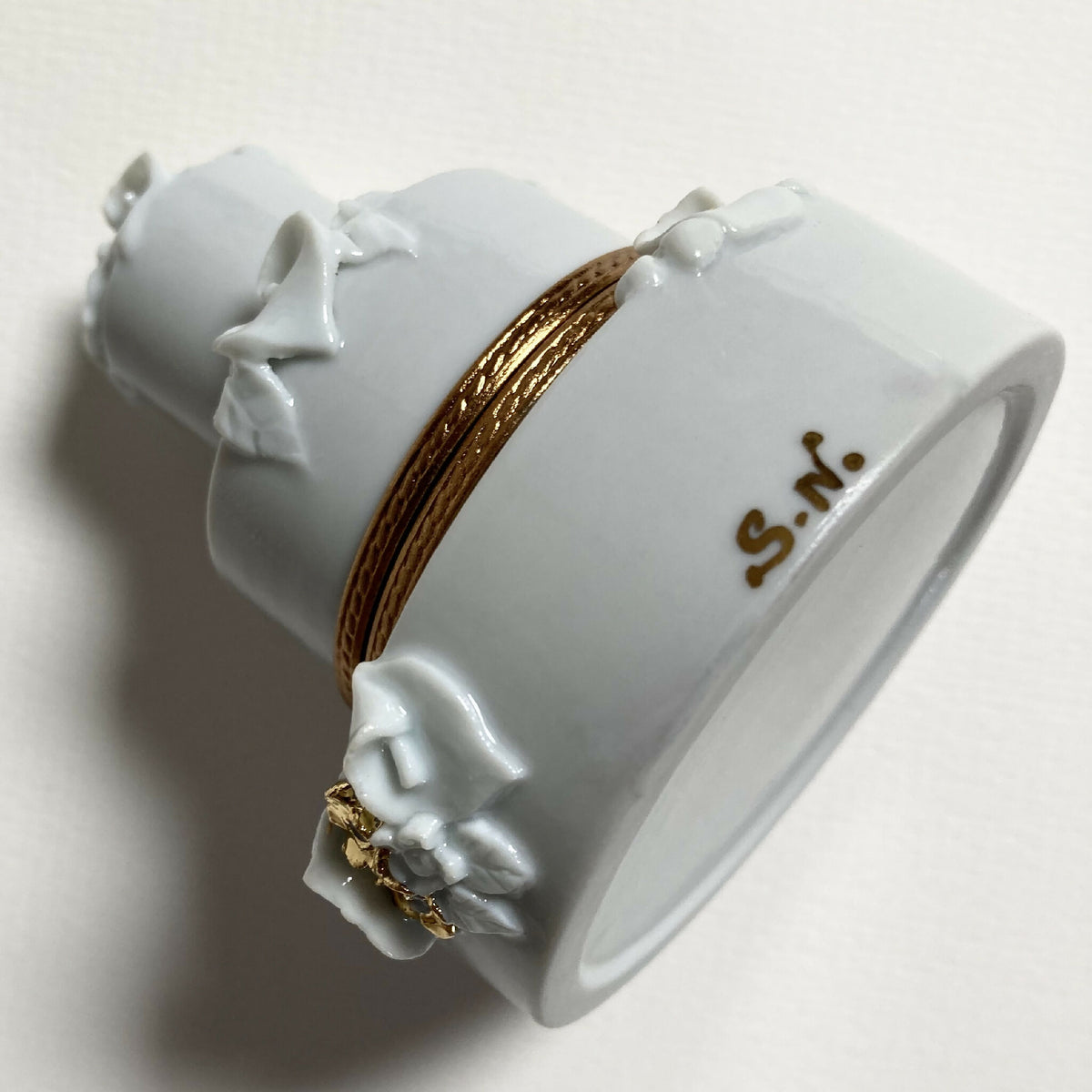 Boîte en porcelaine blanche avec bordure dorée et inscription « S.A. » sur le côté.
