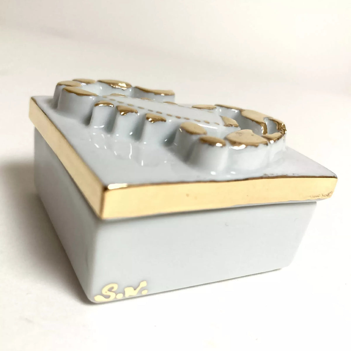 Boîte à bijoux en porcelaine, vue de côté, bord doré et décor scorpion sur le dessus.