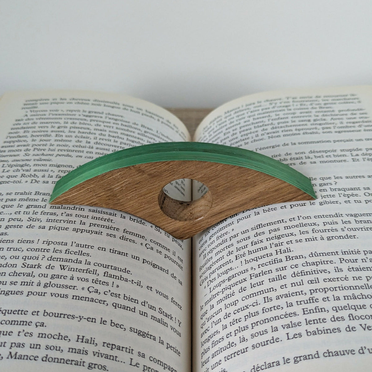 Marque-page en bois à bande verte, posé sur un livre ouvert.