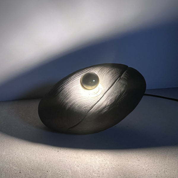 Galet lumineux noir avec LED intégrée, lueur chaude.